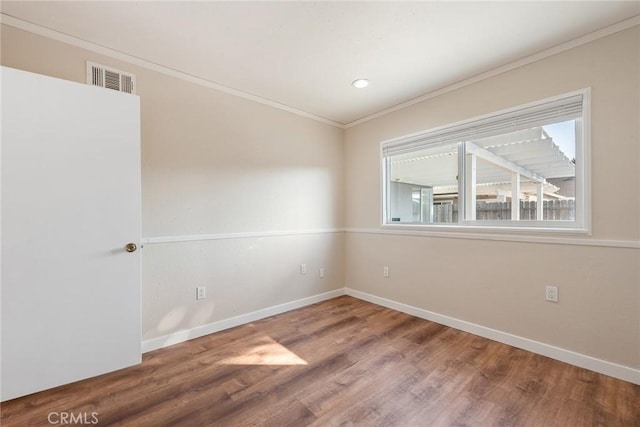 empty room featuring crown molding and hardwood / wood-style flooring