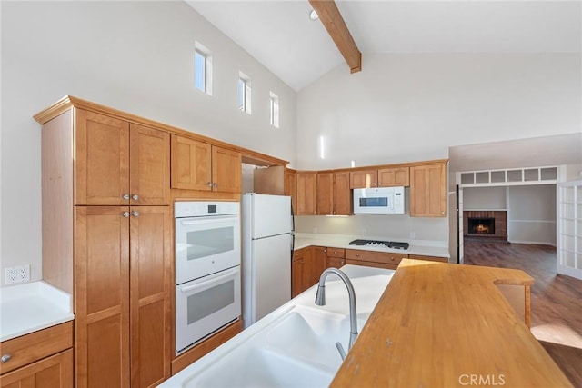 kitchen with high vaulted ceiling, a fireplace, wooden counters, white appliances, and beam ceiling