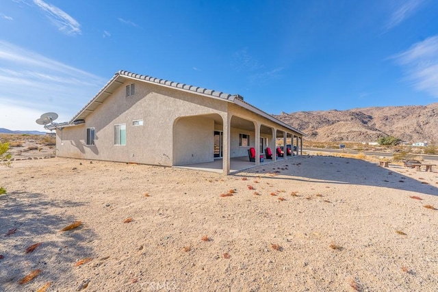 back of house with a mountain view and a patio area