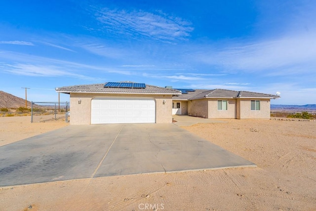 ranch-style house featuring a garage and solar panels