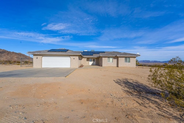 view of front facade featuring a garage, a mountain view, and solar panels