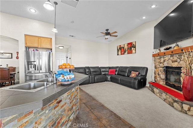 carpeted living room featuring ceiling fan, lofted ceiling, a fireplace, and sink