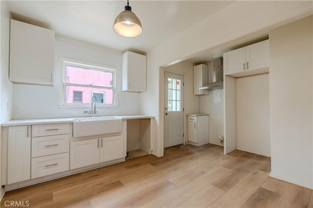 kitchen with sink, white cabinetry, hanging light fixtures, a wealth of natural light, and wall chimney range hood