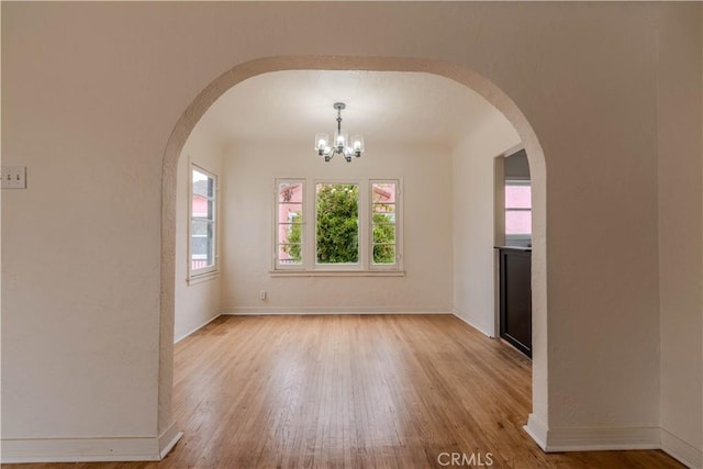 unfurnished dining area featuring a chandelier and light hardwood / wood-style floors