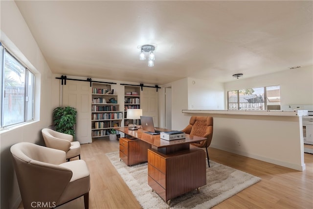 home office with a barn door and light wood-type flooring