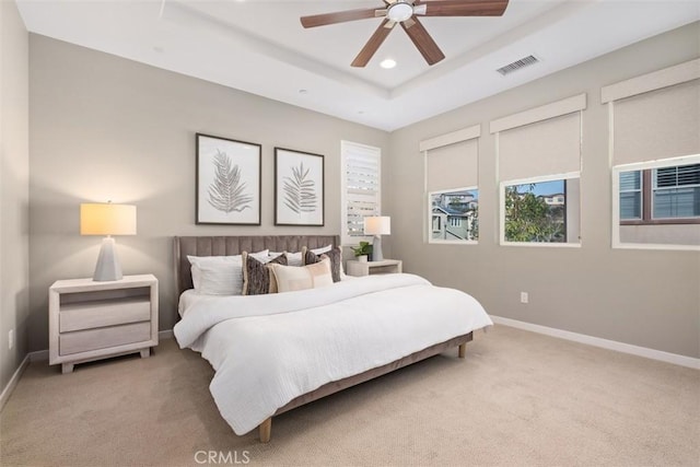 bedroom featuring a tray ceiling, light colored carpet, and ceiling fan