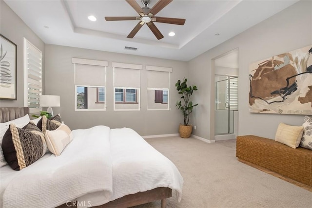 bedroom with ceiling fan, a tray ceiling, and light carpet