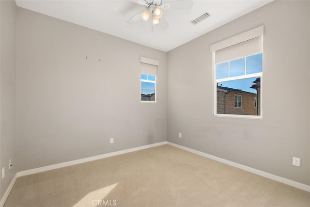 carpeted empty room with a wealth of natural light and ceiling fan