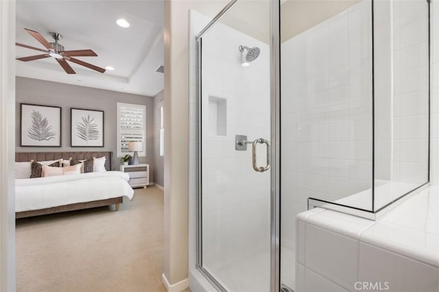 bathroom featuring ceiling fan, a shower with shower door, and a raised ceiling