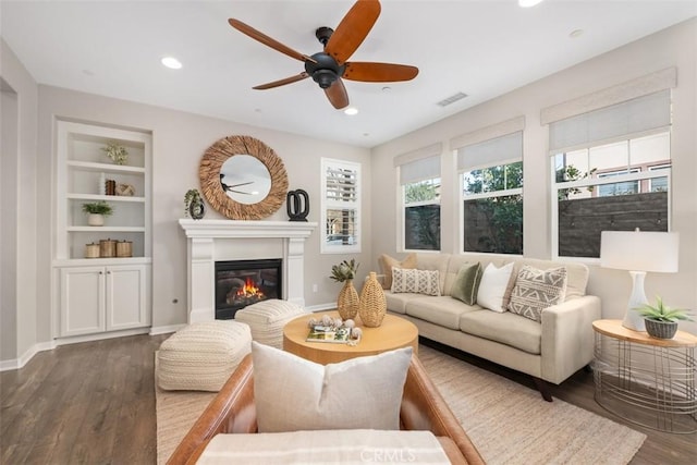 living room featuring built in shelves, ceiling fan, and hardwood / wood-style flooring