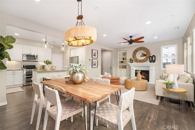 dining space featuring built in shelves, dark hardwood / wood-style floors, and ceiling fan