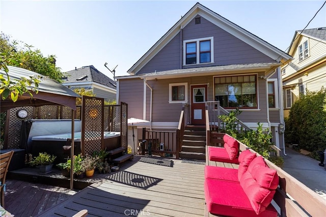 wooden terrace with an outdoor living space, a hot tub, and a gazebo