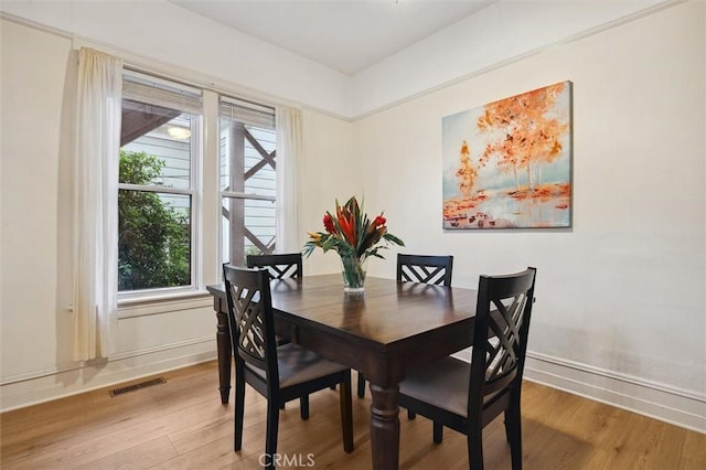 dining area with light wood finished floors, baseboards, and visible vents