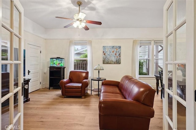 sitting room with light wood-style floors, a ceiling fan, and french doors