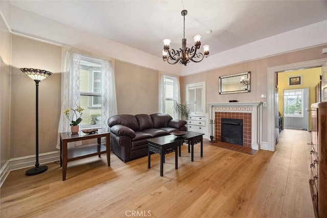 living room with a tiled fireplace, light hardwood / wood-style flooring, and a chandelier