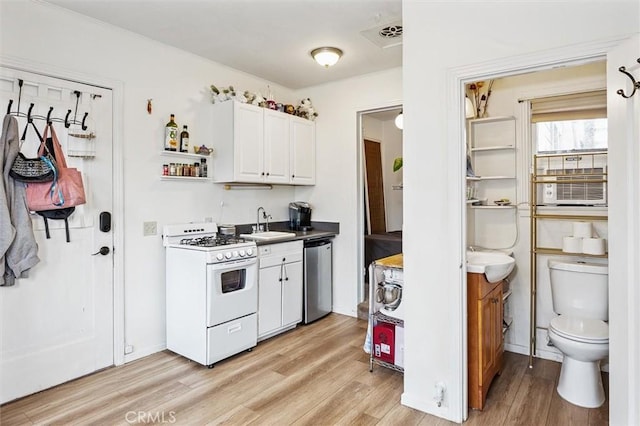 kitchen with light wood finished floors, white range with gas cooktop, visible vents, white cabinets, and dishwasher