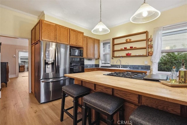 kitchen with black appliances, hanging light fixtures, wooden counters, and crown molding