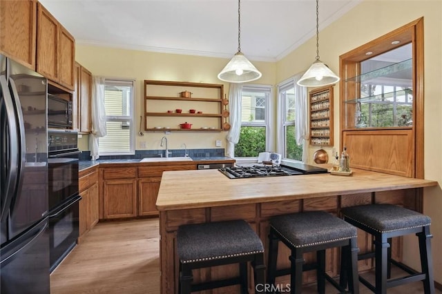 kitchen featuring sink, a wealth of natural light, a kitchen bar, and black appliances