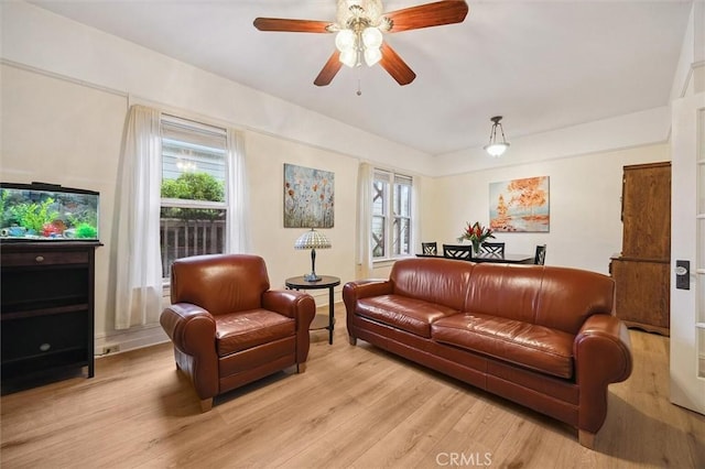 living room featuring ceiling fan, a healthy amount of sunlight, and light wood-type flooring