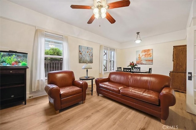 living area featuring a healthy amount of sunlight, light wood finished floors, and ceiling fan