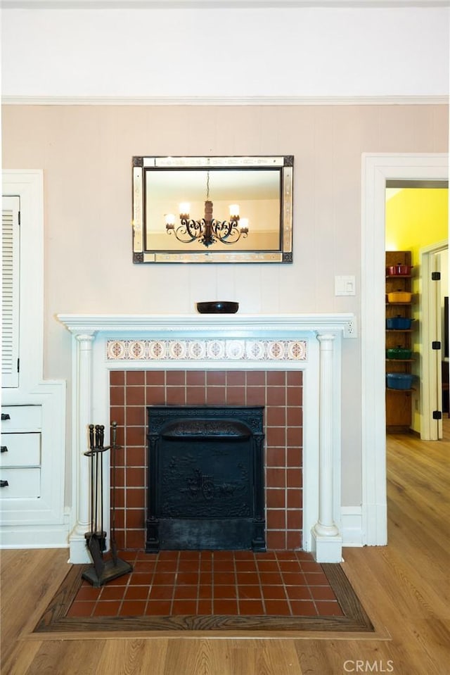 details with a tiled fireplace and wood finished floors