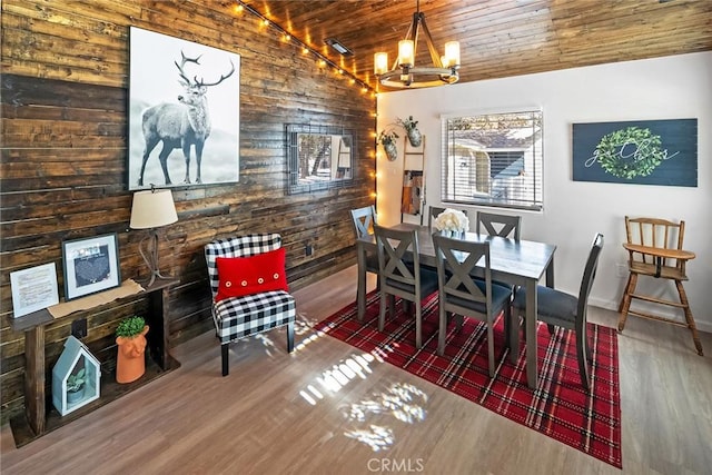 dining room with wooden walls, rail lighting, a chandelier, dark wood-type flooring, and wooden ceiling