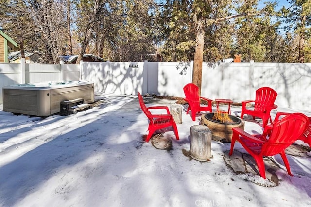 snow covered patio with a hot tub and an outdoor fire pit