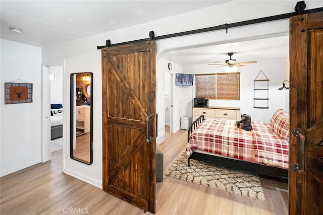 bedroom with a barn door and light hardwood / wood-style flooring