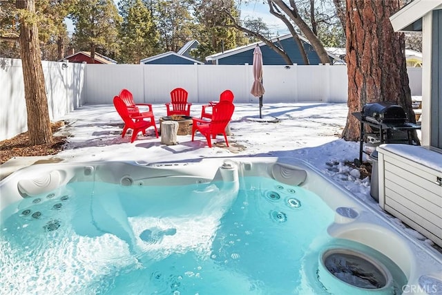 snow covered pool featuring a hot tub and a fire pit