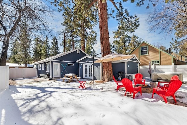 snow covered back of property with a hot tub and french doors