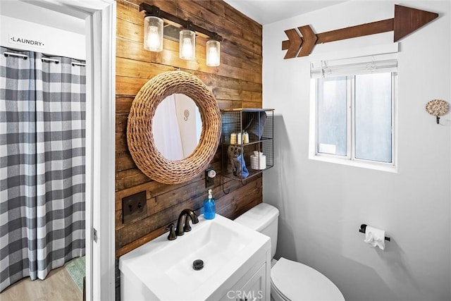 bathroom with toilet, sink, and wood walls