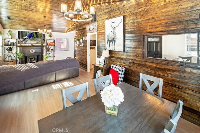 dining area featuring a notable chandelier, light wood-type flooring, and wood ceiling