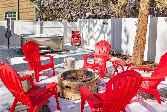 snow covered patio with an outdoor fire pit and a hot tub