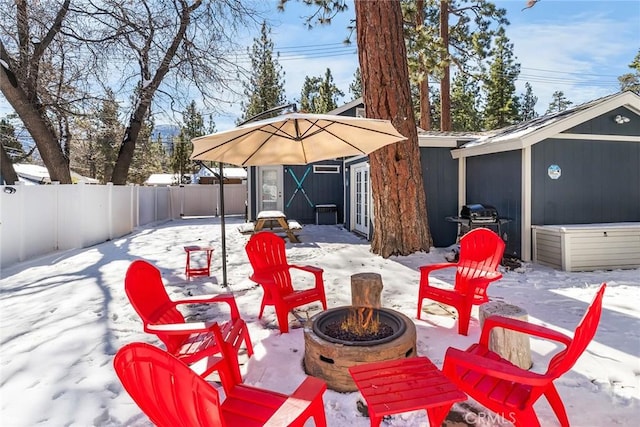 snow covered patio with an outbuilding, a fire pit, and area for grilling