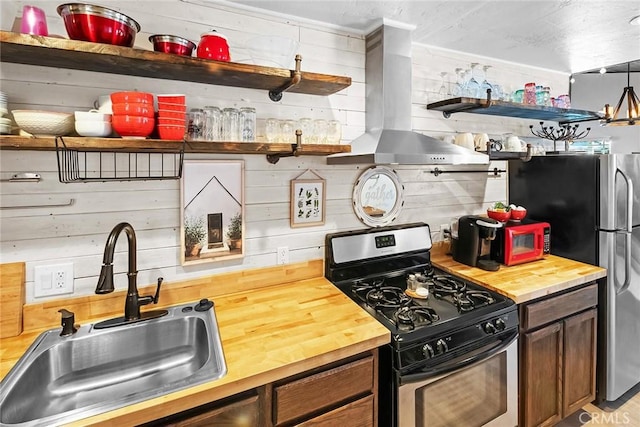 kitchen featuring island exhaust hood, appliances with stainless steel finishes, sink, and butcher block countertops