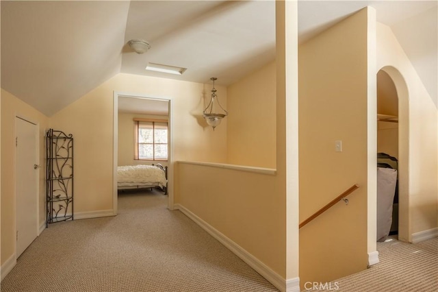 hall featuring light carpet and vaulted ceiling