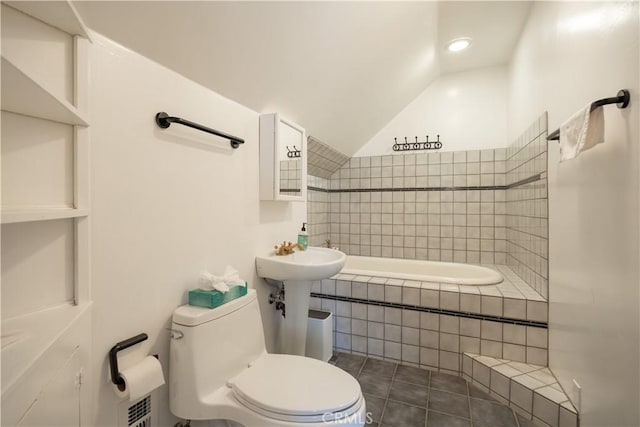 bathroom featuring tile patterned floors, lofted ceiling, toilet, and tiled bath