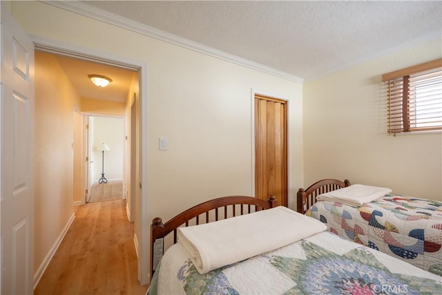 bedroom with crown molding, a closet, a textured ceiling, and light wood-type flooring