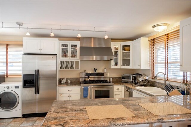 kitchen featuring stainless steel appliances, washer / dryer, exhaust hood, and white cabinets