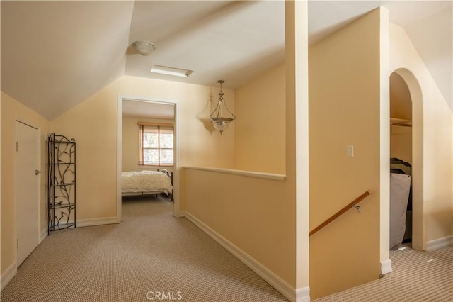 corridor featuring lofted ceiling and light colored carpet