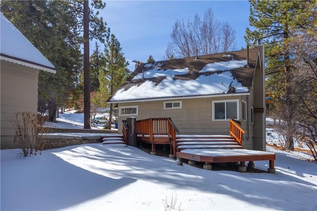 snow covered rear of property with a wooden deck