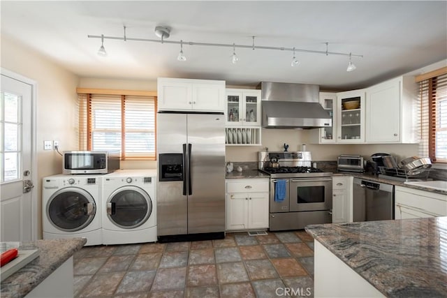 kitchen with white cabinetry, washer and clothes dryer, wall chimney exhaust hood, and appliances with stainless steel finishes