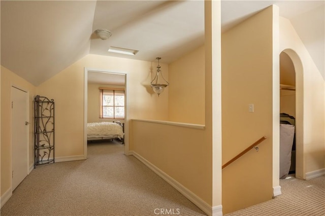 corridor with vaulted ceiling and light colored carpet