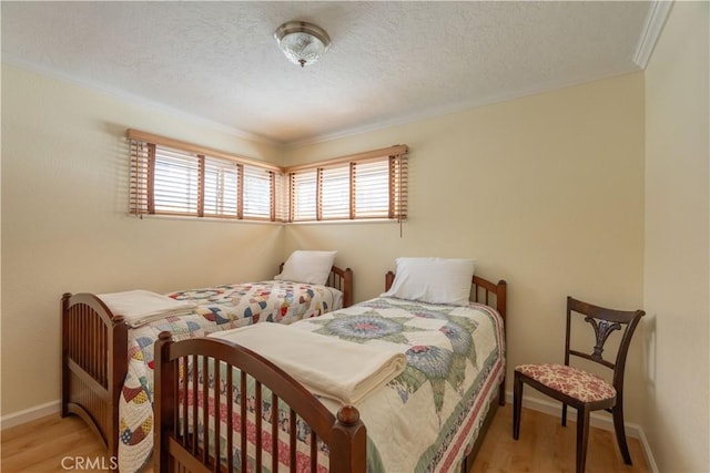 bedroom with crown molding, light hardwood / wood-style flooring, and a textured ceiling