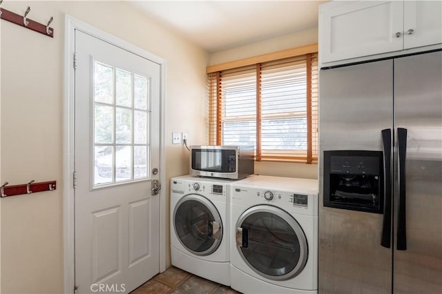 laundry area featuring plenty of natural light, washing machine and dryer, cabinets, and dark tile patterned floors