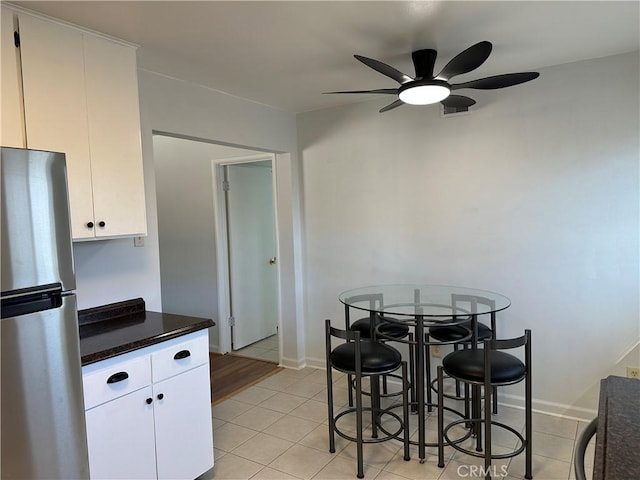 kitchen with white cabinetry, stainless steel refrigerator, ceiling fan, and light tile patterned flooring