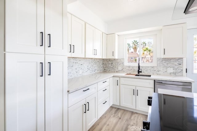 kitchen featuring sink, dishwasher, white cabinetry, backsplash, and light wood-type flooring