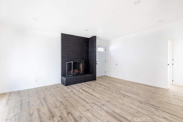 unfurnished living room with a brick fireplace and light hardwood / wood-style floors