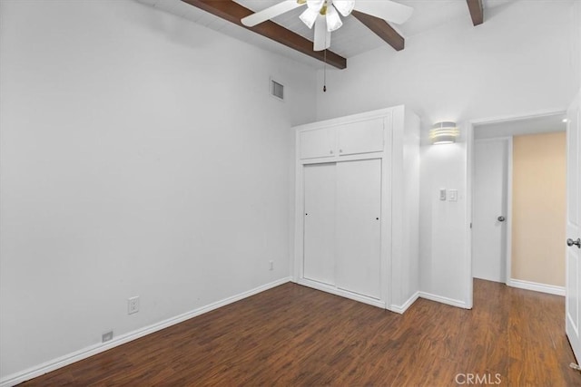 unfurnished bedroom featuring vaulted ceiling with beams, dark wood-type flooring, a closet, and ceiling fan