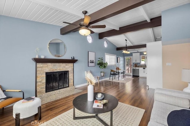 living room featuring dark hardwood / wood-style flooring, a stone fireplace, lofted ceiling with beams, and ceiling fan